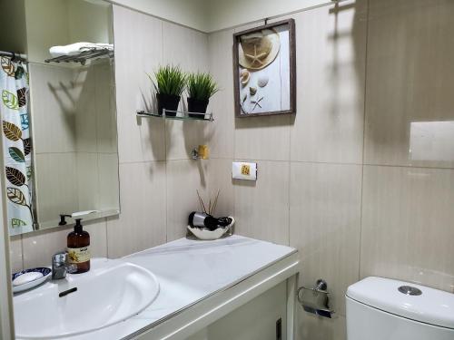 a bathroom with a sink and a toilet and a mirror at Shell Residence Manila in Manila