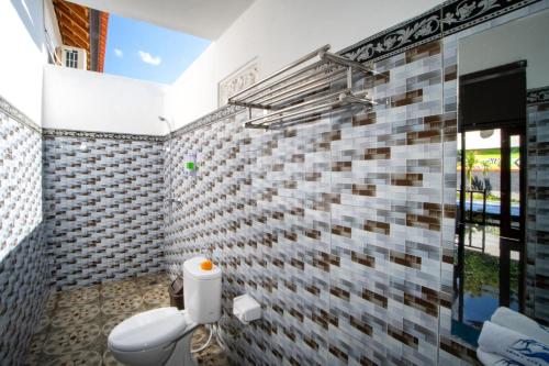 a bathroom with a toilet and a brick wall at Sundi Ocean Bungalow by ABM in Nusa Penida