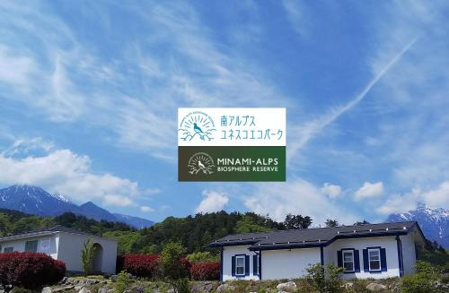 a sign for a house with mountains in the background at Alps Lodge & Spa in Hokuto