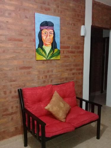 a red couch against a brick wall with a painting at CASA Zona Huarpe Hospedaje in Albardón