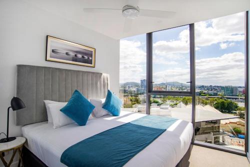 a bedroom with a large bed with a large window at Brisbane One Apartments by CLLIX in Brisbane