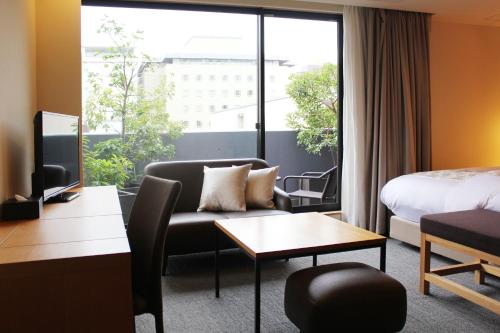 a hotel room with a couch and a bed and a window at Villa Sanjomuromachi KYOTO in Kyoto