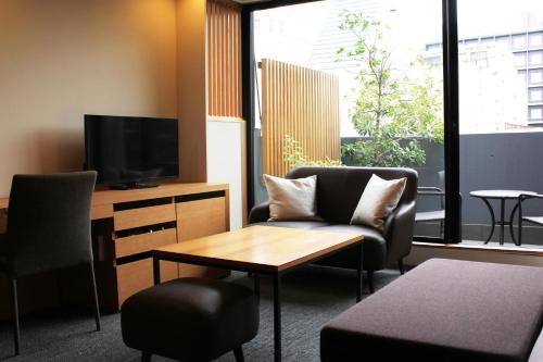 a living room with a couch and a tv and a table at Villa Sanjomuromachi KYOTO in Kyoto