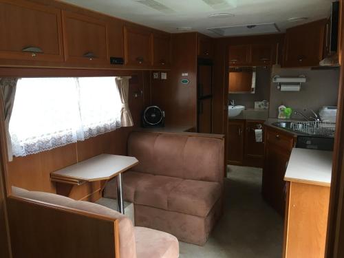 Comfortable caravan في كوكتاون: غرفة معيشة مع أريكة ومطبخ