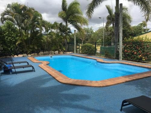 a large swimming pool with a wooden coping around it at Comfortable caravan in Cooktown