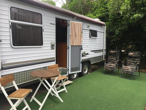una cabaña con mesa y sillas junto a ella en Comfortable caravan, en Cooktown