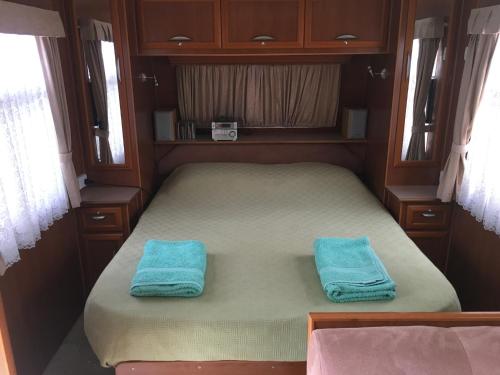Cama pequeña en habitación pequeña con toallas azules en Comfortable caravan, en Cooktown
