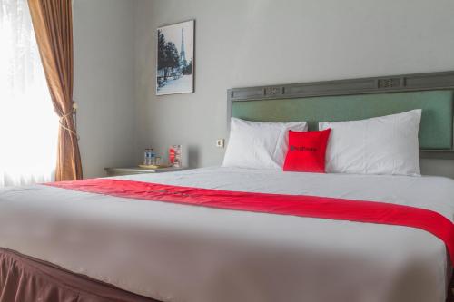 a bedroom with a large white bed with a red pillow at RedDoorz Plus @ Otista Garut in Garut