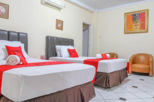 two beds in a room with red and white at RedDoorz Plus @ Otista Garut in Garut