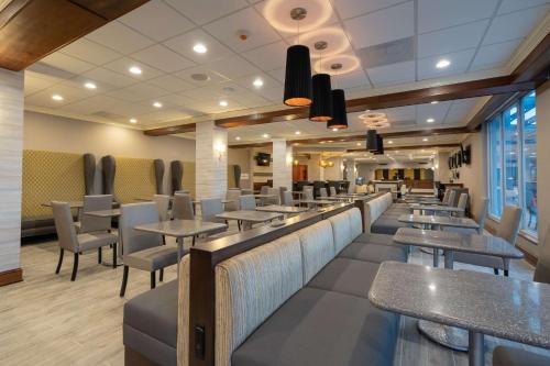 a restaurant with tables and chairs and a bar at Cottonwood Airport & Expo Hotel Louisville in Louisville