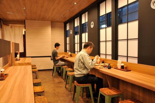 two men sitting at a bar in a restaurant at Matsumoto Tourist Hotel in Matsumoto