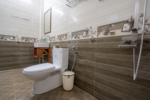 a bathroom with a toilet and a wall with wooden tiles at Fami Homestay in Phong Nha