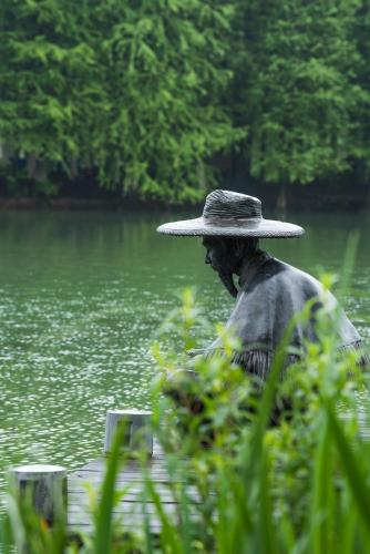 a person wearing a hat sitting in front of a body of water at Fairmont Yangcheng Lake in Kunshan