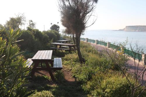 a group of picnic tables next to the ocean at Seaside Apartments in Marsaskala
