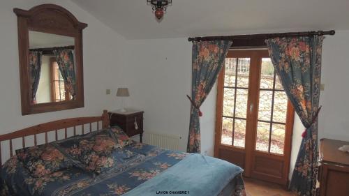 1 dormitorio con cama, espejo y ventanas en Gîte Layon 6 places Moulin de la Placette, en Faye-dʼAnjou