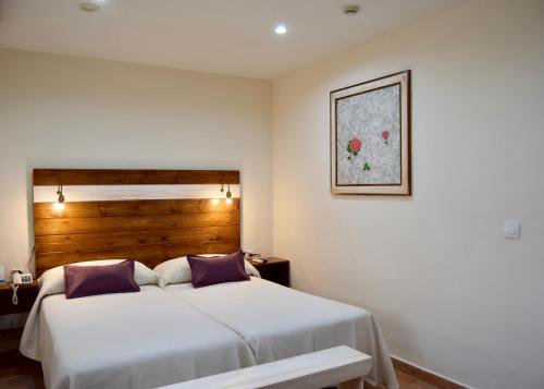 a bedroom with a large white bed with purple pillows at Puerta de Algadir in El Puerto de Santa María
