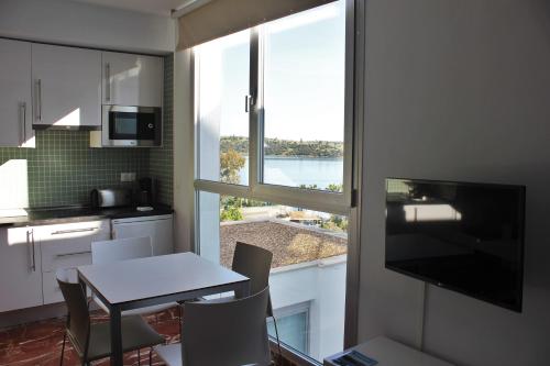eine Küche mit einem Tisch und Stühlen sowie einem Fenster in der Unterkunft Apartamentos Embalse de Orellana in Orellana la Vieja