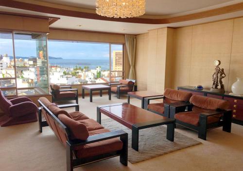 a living room filled with furniture and a large window at Atami Kinjokan in Atami