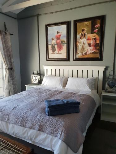 a bedroom with a large bed with two pictures on the wall at At Rest in Zeerust