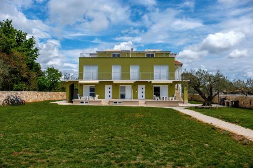 a large yellow house with a lawn in front of it at Apartments Nogic in Peroj