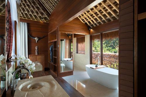 a bathroom with two sinks and a tub and a bath tub at Lelewatu Resort Sumba in Watukarere