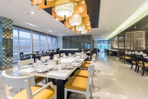 a dining room with white tables and yellow chairs at Kantary Hotel Korat in Nakhon Ratchasima