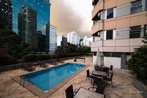 a swimming pool with tables and chairs next to a building at Flat Premier 14 Max Savassi in Belo Horizonte