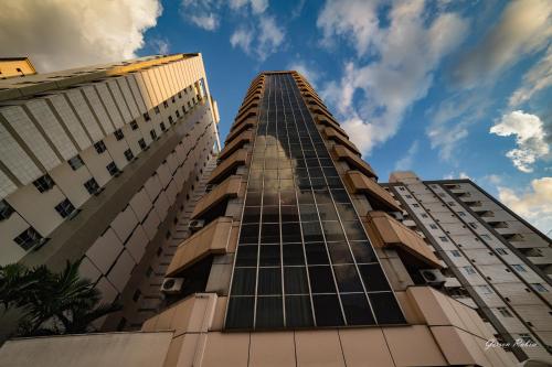 zwei hohe Gebäude gegen einen blauen Himmel mit Wolken in der Unterkunft Flat Premier 14 Max Savassi in Belo Horizonte