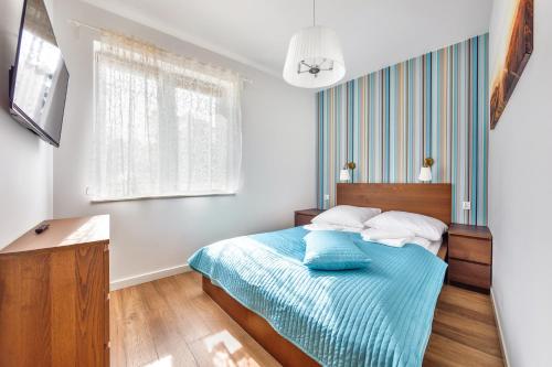 a bedroom with a bed with a blue blanket at Dwie Sosny z sauną, Sun & Snow in Ustronie Morskie