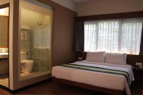 a bedroom with a bed with a window and a bathroom at Grand Whiz Hotel Nusa Dua Bali in Nusa Dua