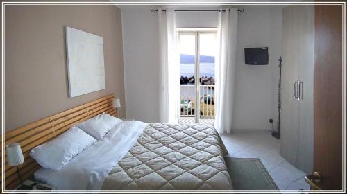 トッレ・ファロにあるCasa Siciliaのベッドルーム1室(ベッド1台付)、バルコニーへのドアが備わります。