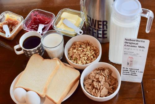 Noboribetsu Guest House AKA & AO في نوبوريبيتسو: طاولة مع خبز البيض المحمص وأطعمة الإفطار الأخرى