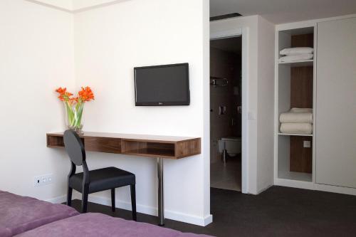a bedroom with a desk and a tv on a wall at Hotel Regina in Fátima