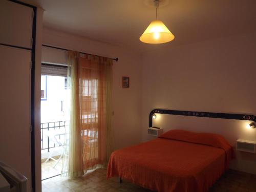 a bedroom with a bed with a orange bedspread and a window at Residencia Laranjeira in Odeceixe
