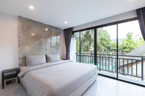 a bedroom with a large bed and a large window at Minimal House Patong in Patong Beach