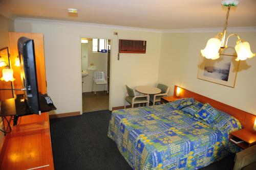 a hotel room with a bed and a table and a bathroom at Mildura Plaza Motor Inn in Mildura