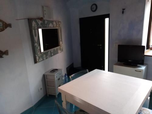 Habitación con mesa blanca, TV y ventana. en Isola del Giglio, en Giglio Porto