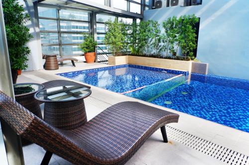 a swimming pool in a building with chairs and a table at Valero Grand Suites by Swiss-Belhotel in Manila