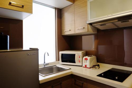 a small kitchen with a sink and a microwave at Valero Grand Suites by Swiss-Belhotel in Manila