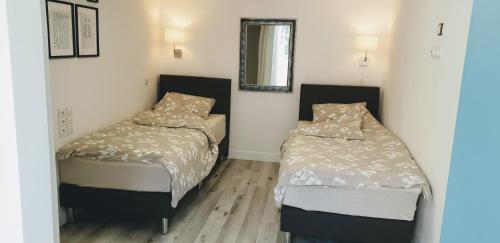 two beds in a small room with a mirror at Gaia Studio in Wrocław
