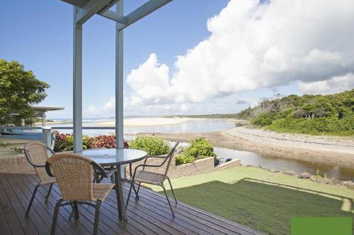 a table and chairs on a deck with a view of a river at Nosie 1 in Sawtell