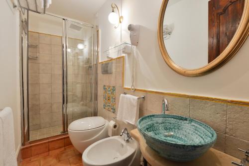 a bathroom with a sink and a toilet and a mirror at San Francesco Resort in Agropoli