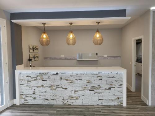 a kitchen with pendant lights and a stone wall at Casa Orilla el Lago in Córdoba