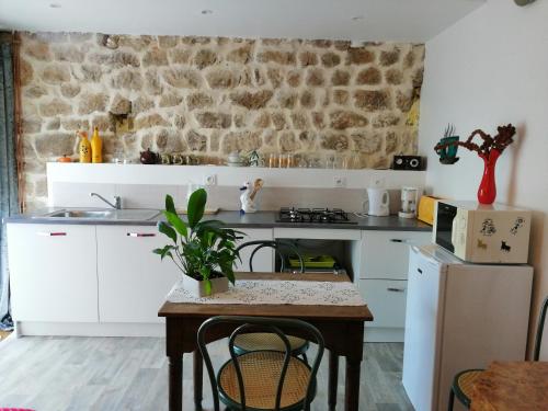 uma cozinha com uma mesa e uma parede de pedra em L'Ancienne Ecole em Silhac