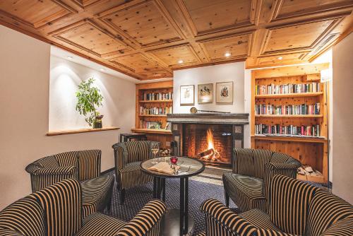 a living room with chairs and a fireplace at Hotel Post Sils Maria in Sils Maria