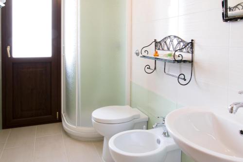 La salle de bains blanche est pourvue de toilettes et d'un lavabo. dans l'établissement S'eredeu Apartments, à Sestu