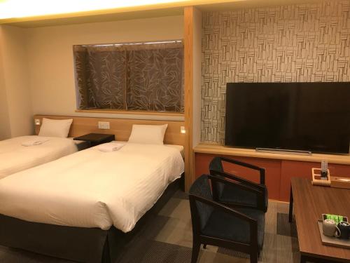 a hotel room with two beds and a flat screen tv at Hotel Yururito Osaka in Osaka
