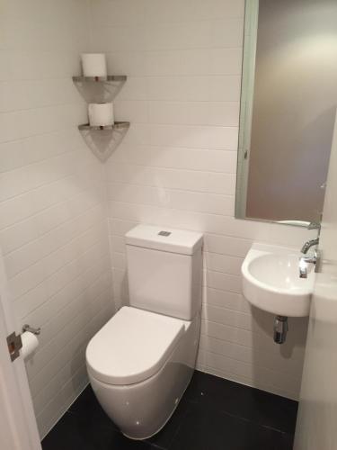 a white bathroom with a toilet and a sink at Museum Apartment in Wellington