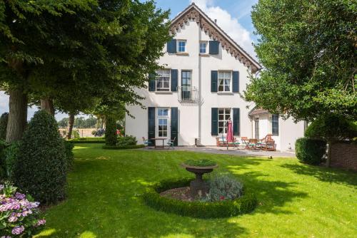 een groot wit huis met een vogelbad in de tuin bij Gastenverblijf de Korenhorst in Lengel