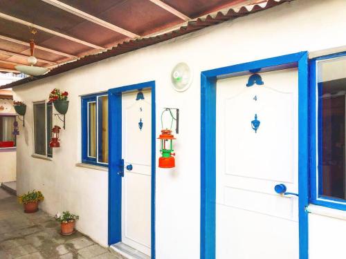 a white house with blue doors and windows at Ozdemir Pansiyon in Heybeliada
